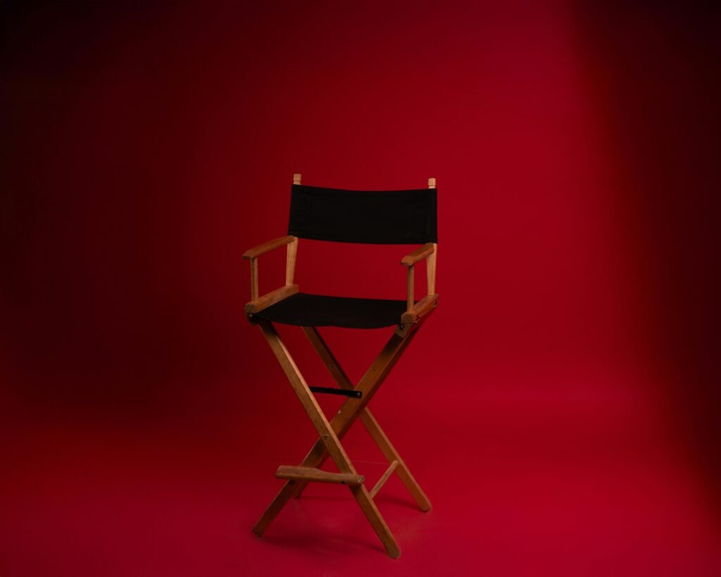 A wooden director's chair against a vibrant red backdrop, symbolizing film industry authority.